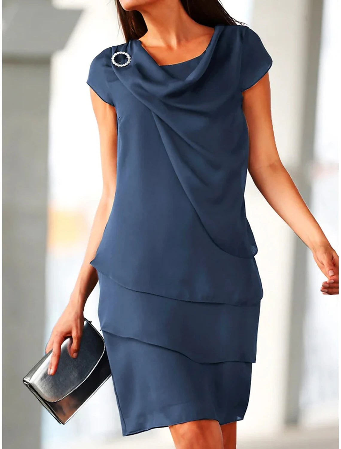 Woman wearing an elegant navy blue short sleeve ruched midi shift dress, back view.