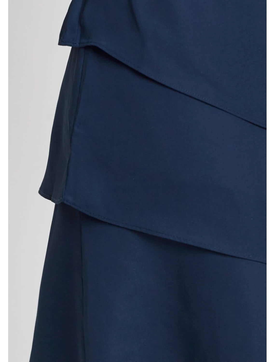 Close-up of the ruched and layered fabric detail on the navy blue midi dress.