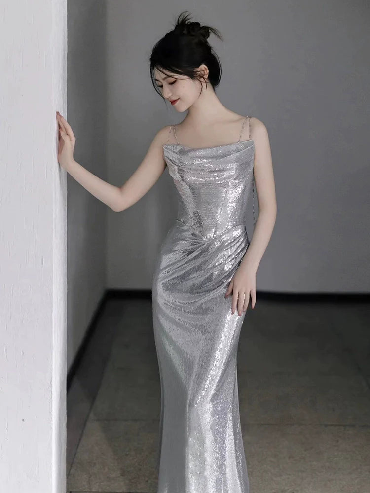 Side view of a model wearing a silver sequin mermaid evening dress with spaghetti straps.