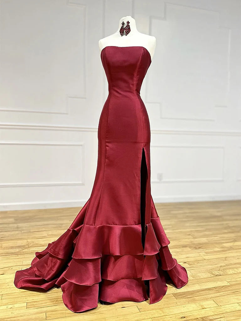 Woman wearing an elegant sleeveless burgundy mermaid satin long prom dress.