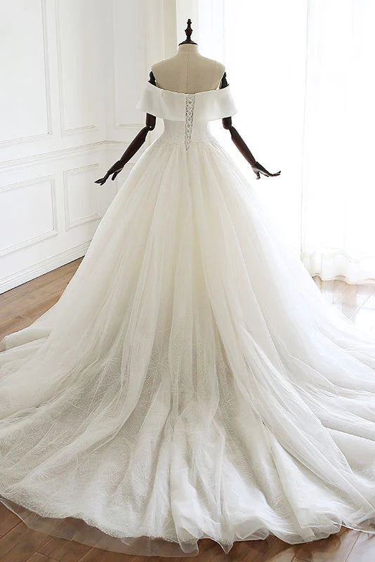 Close-up of the bodice and flowing skirt of a white tulle bridal dress.