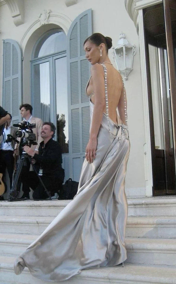 Woman in a long black backless evening gown, side profile.