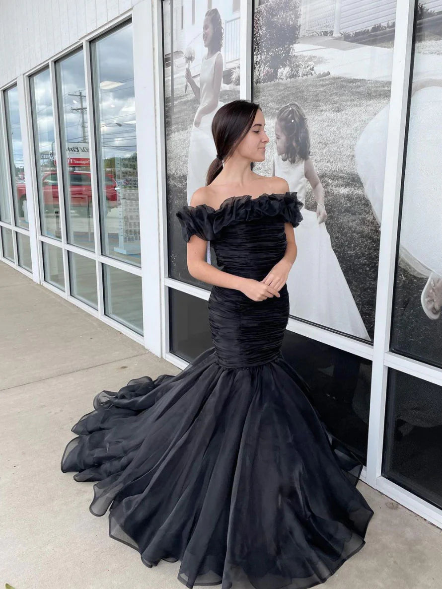 Woman wearing a black off-shoulder tulle mermaid long prom dress.