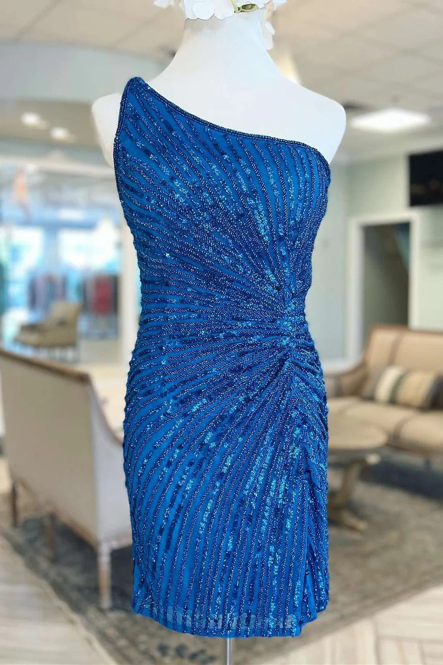 Front view of a woman wearing an elegant blue one-shoulder beaded mini cocktail dress.