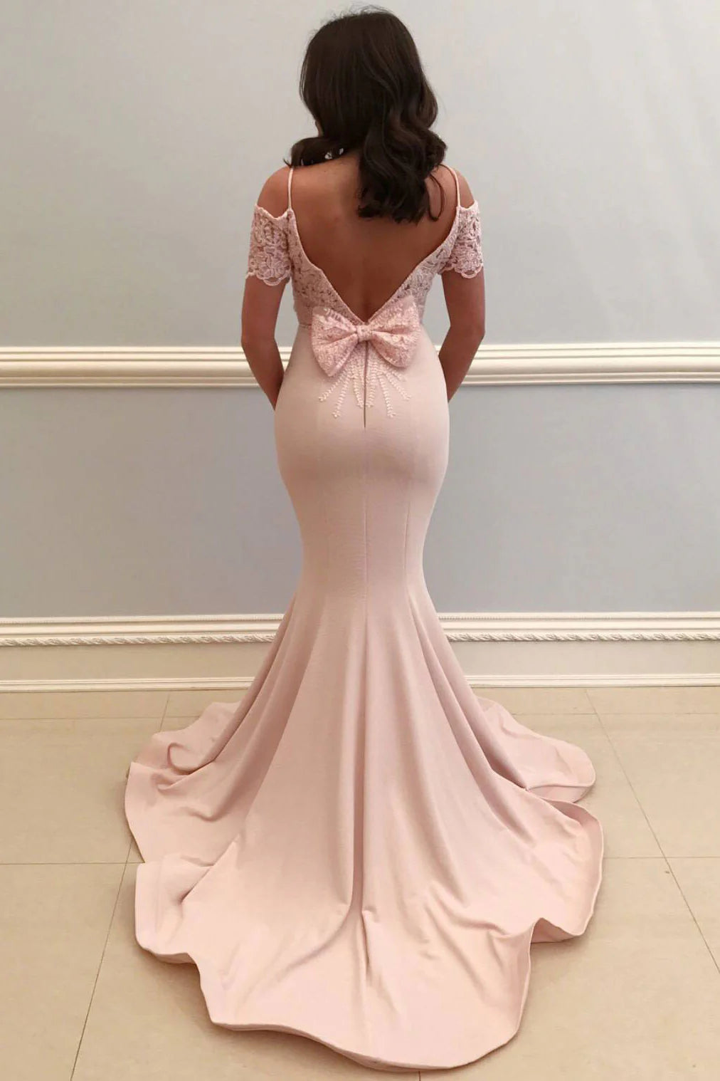 Woman wearing a pink satin mermaid long prom dress, side view.