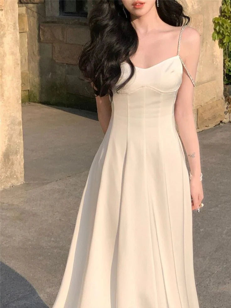 Side view of a woman in a chic spaghetti strap midi dress.