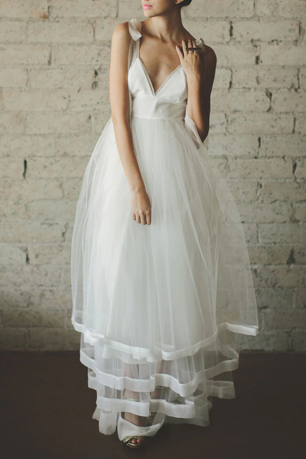Woman wearing an elegant white V-neck tulle prom dress with lace applique.
