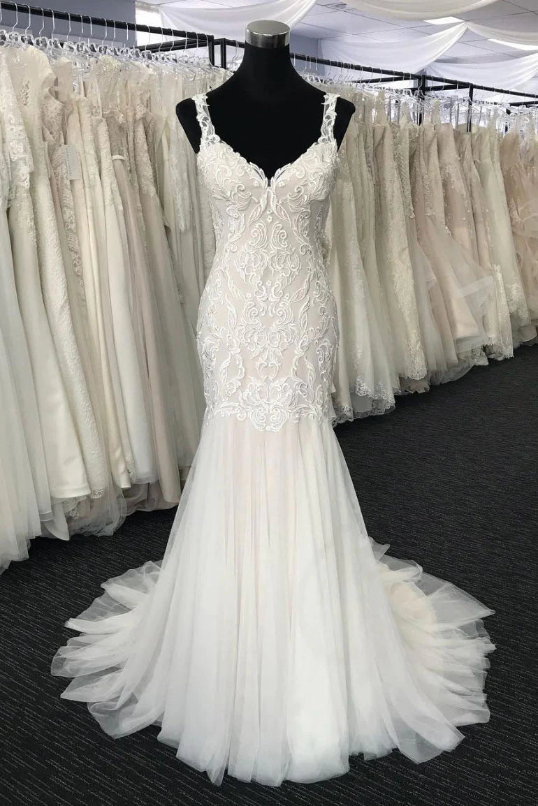 Woman wearing a white lace and tulle mermaid prom or wedding dress.