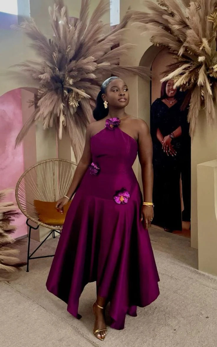 Woman wearing a purple halter slim-fit maxi prom dress with applique details.