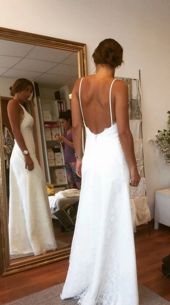 Model wearing a white slim-fit lace backless wedding dress with spaghetti straps.