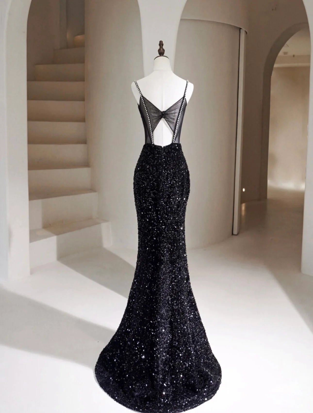 Side view of a woman in a black sequin mermaid long formal dress.