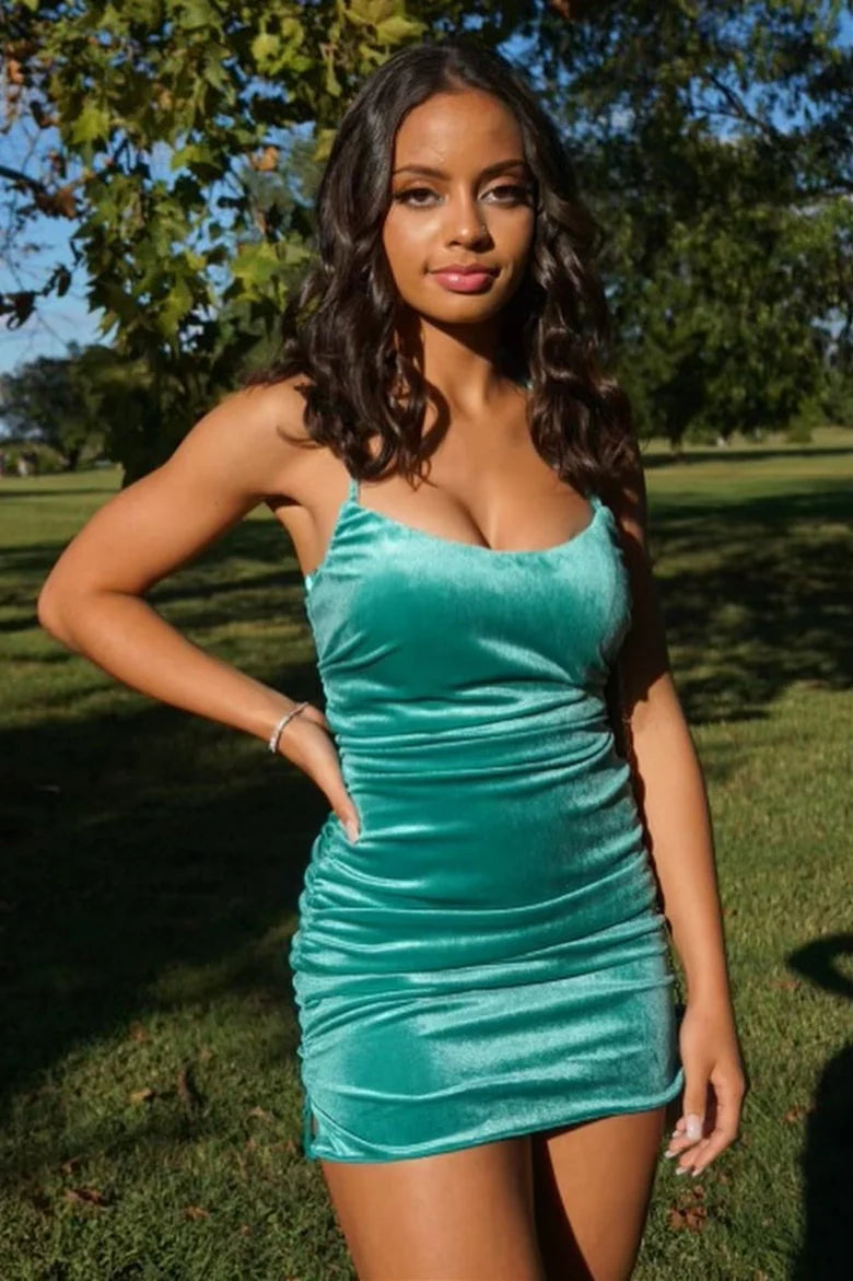 Woman wearing a turquoise slim-fit velvet party dress with spaghetti straps and a lace-up side slit.