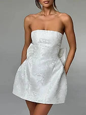 Woman wearing an elegant solid color strapless homecoming dress with a bow tie.