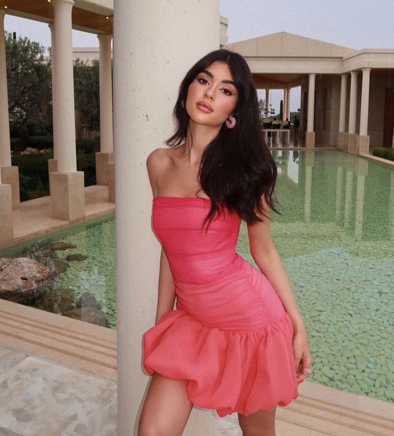 Woman wearing an elegant strapless ruched mini cocktail dress.