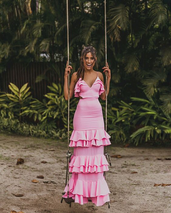 Model wearing an elegant pink long ball gown with thin shoulder straps and a full skirt.