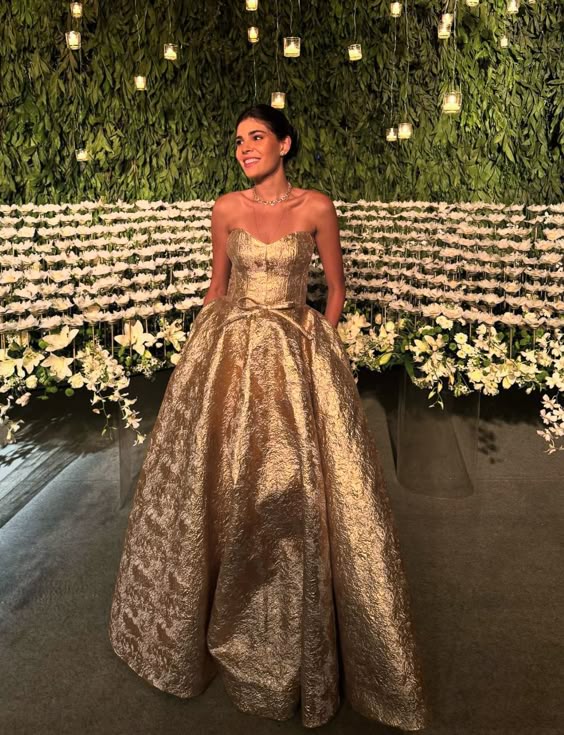 Model wearing a gold sweetheart sleeveless floor-length ball gown.