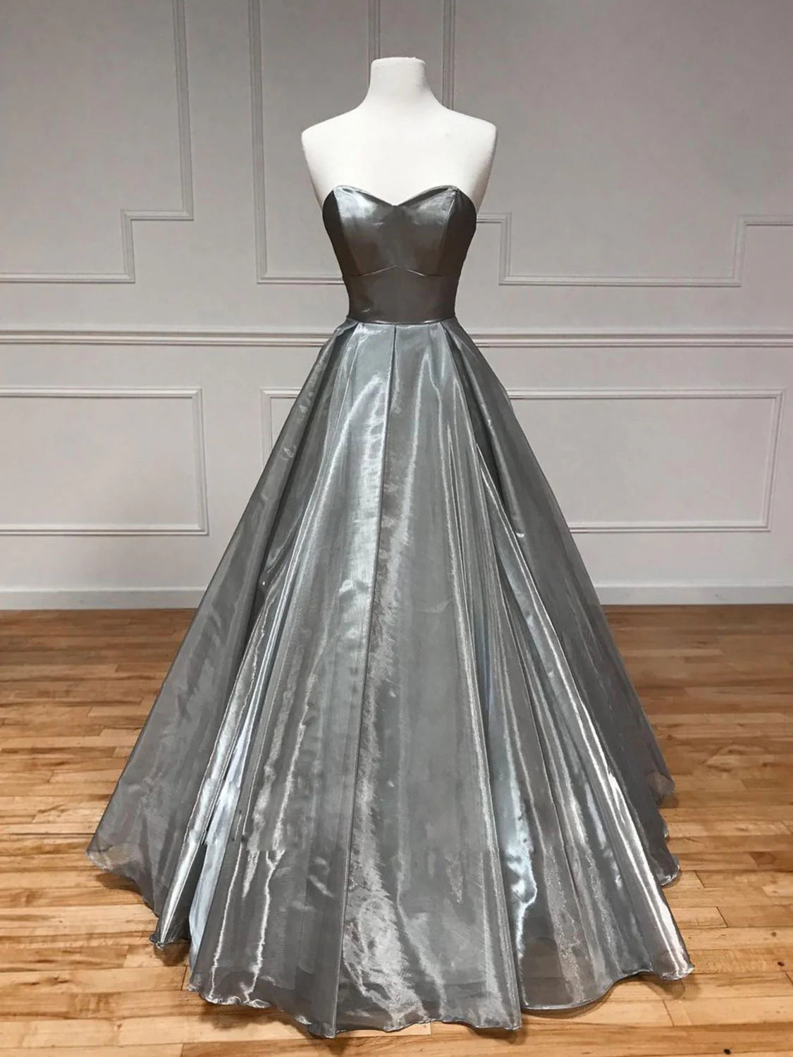 Woman wearing an elegant gray sweetheart neck A-line long satin prom dress.