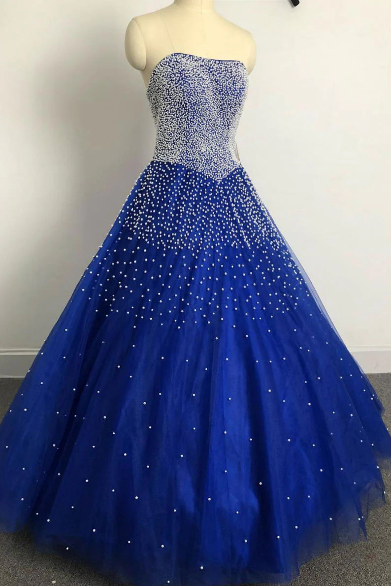 Woman wearing an elegant long blue sweetheart tulle beaded prom dress.