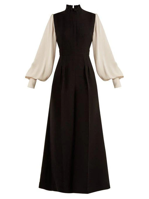 Elegant woman wearing a black long sleeve half high neck ball gown with a cinched waist.