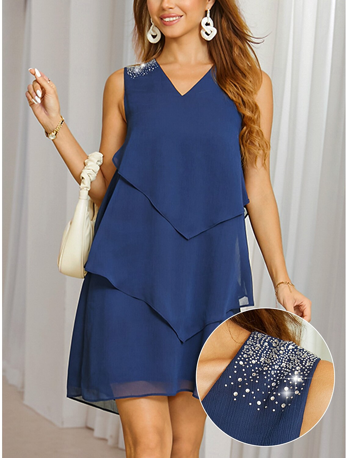 Woman wearing an elegant navy blue tiered chiffon mini dress with sequin details and a V-neckline.
