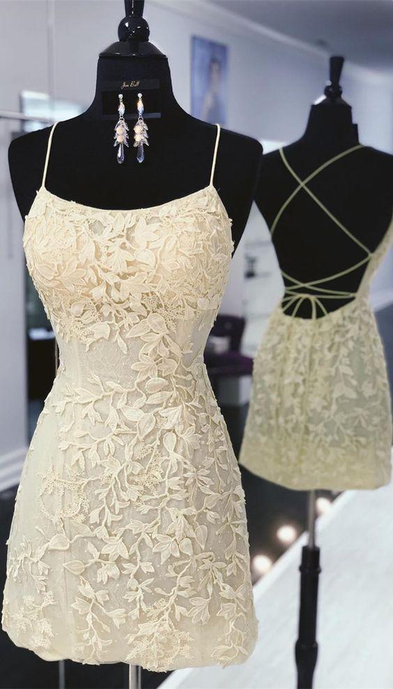 Model wearing a tight yellow lace short backless dress with thin shoulder straps.