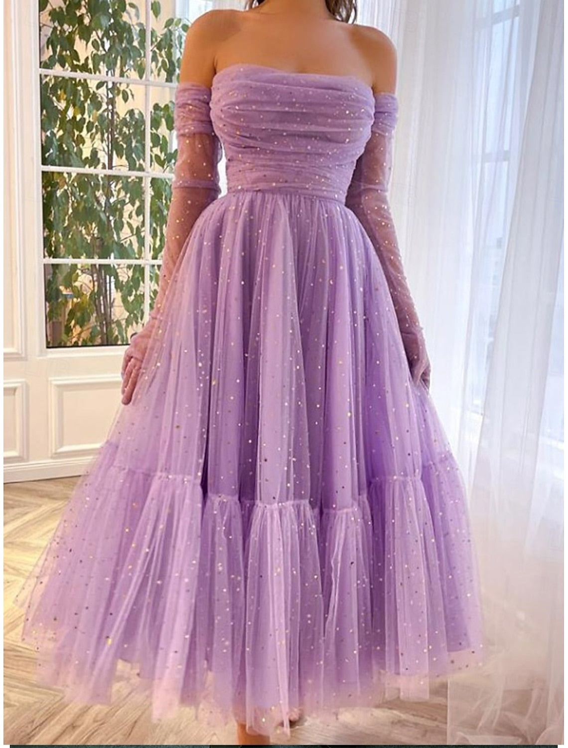 Woman wearing an elegant purple off-shoulder tulle maxi dress, front view.
