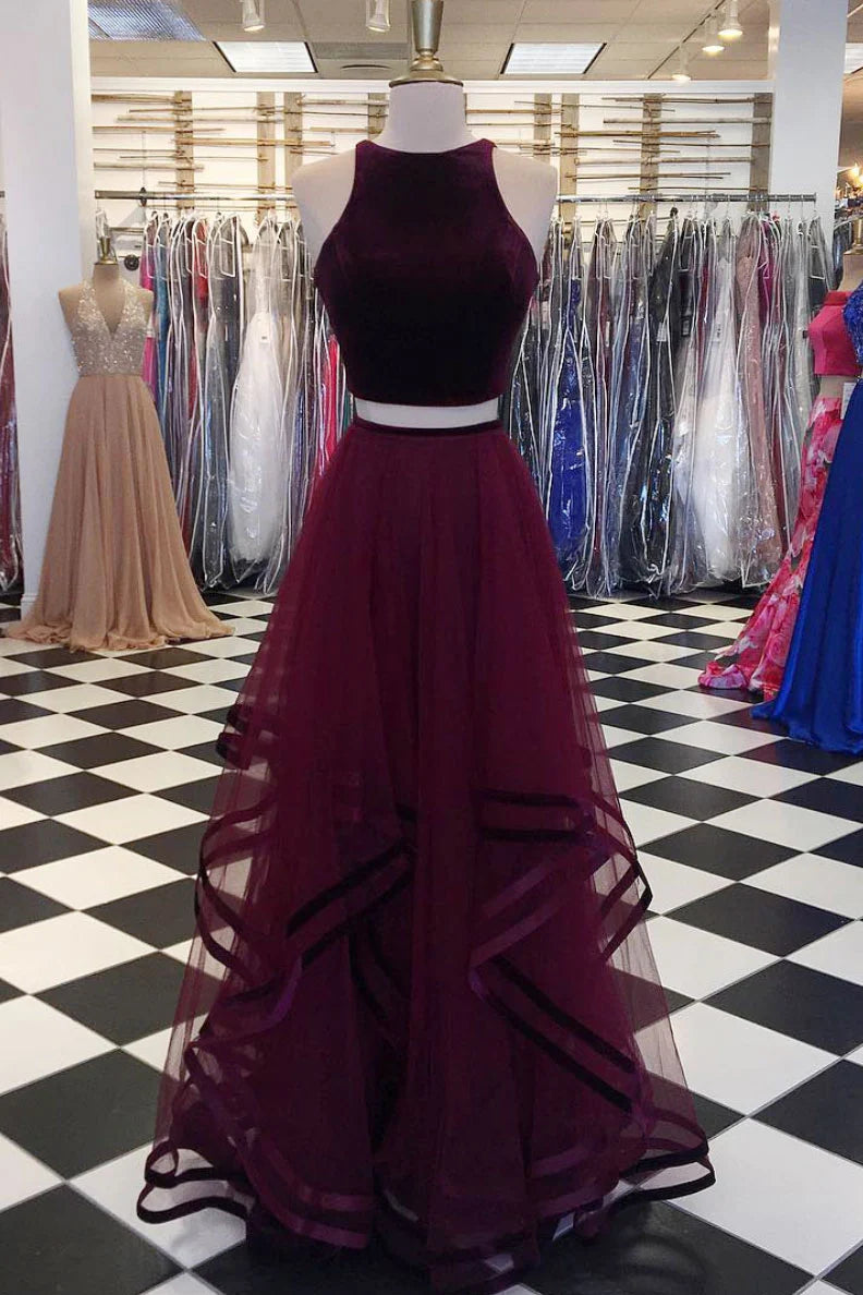 Model wearing a burgundy two-piece long prom dress with a sleeveless top and A-line skirt, showcasing the waist.