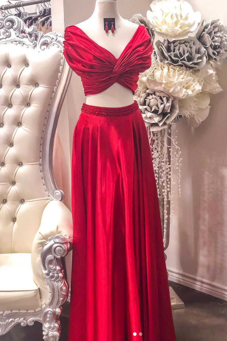 Woman wearing a red two-piece satin long prom dress with a waist-revealing design.