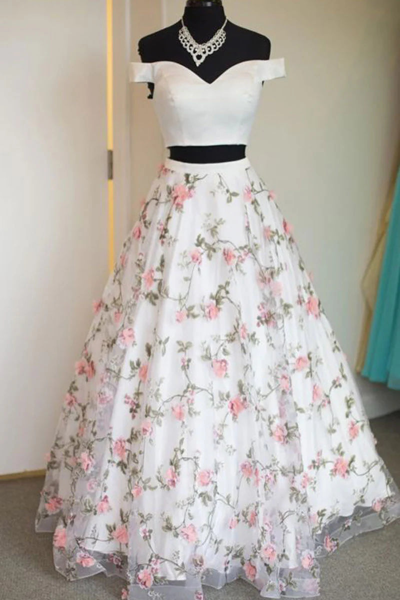 Model wearing a white two-piece long tulle prom dress with a waist-revealing design.