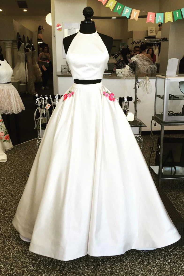 Woman wearing an elegant white two-piece satin long prom dress with delicate applique.