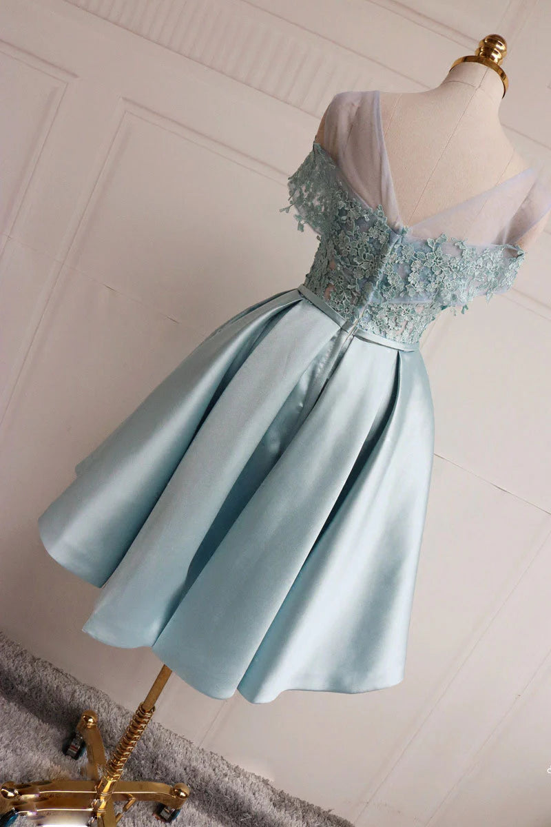 Close-up of the intricate blue lace fabric and V-neckline of the short dress.