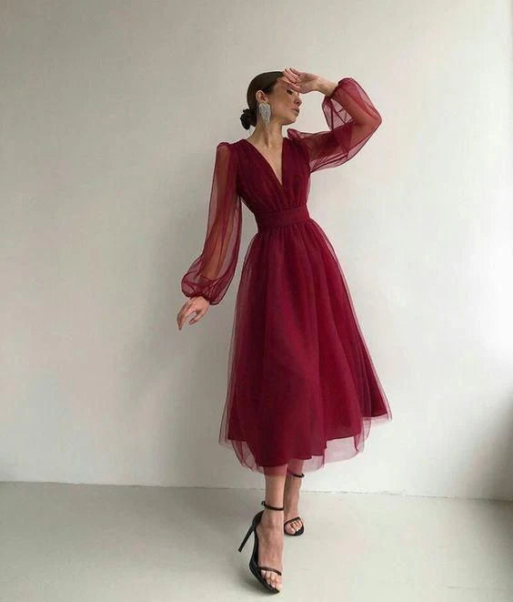 A woman wearing a long, elegant V-neck A-line prom dress in a light color.