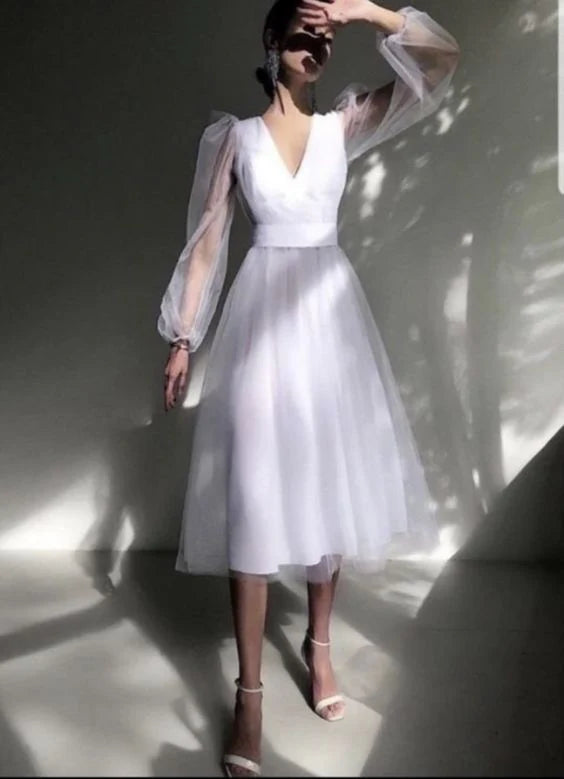 A woman in a long, flowing prom dress with a V-neck and sleeveless design.