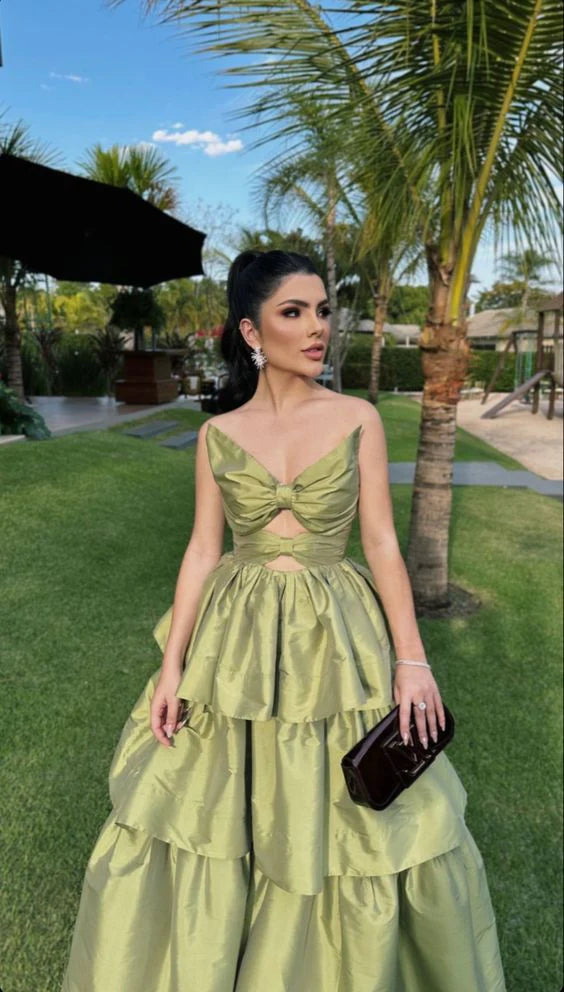 Woman wearing an elegant sage green A-line satin V-neck guest wedding dress, front view.