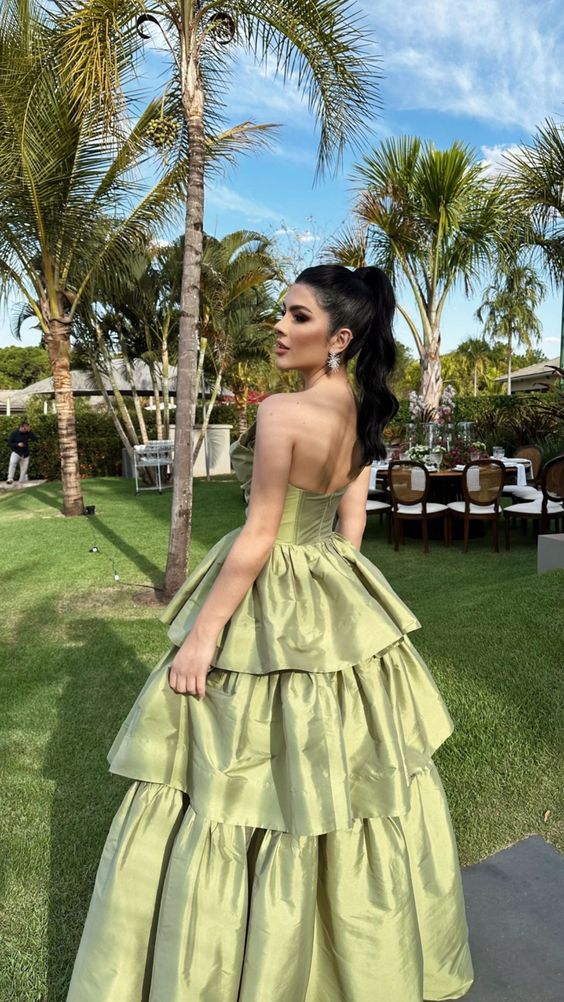 Back view of a woman in a floor-length sage green A-line satin dress.