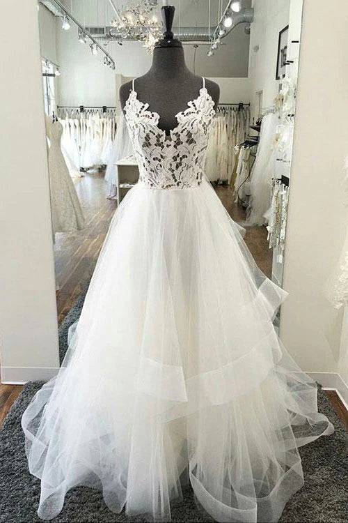 Woman wearing an elegant white V-neck lace and tulle long prom dress.