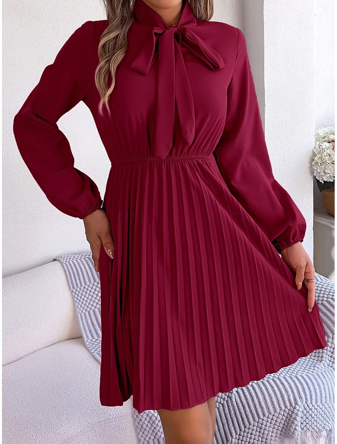 Woman showcasing the back view of the long sleeve V-neck mini dress.
