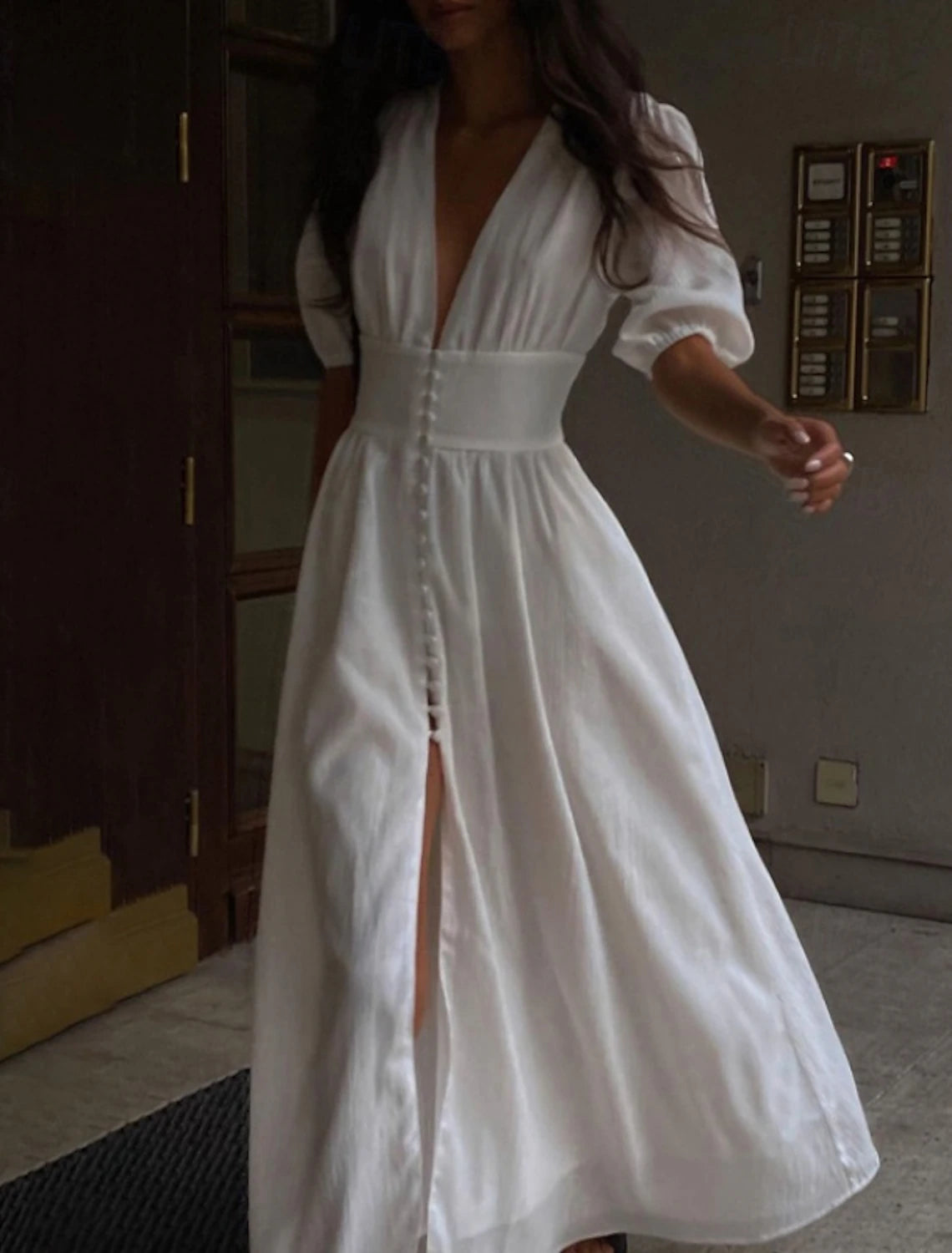 Woman posing in an elegant white midi dress.
