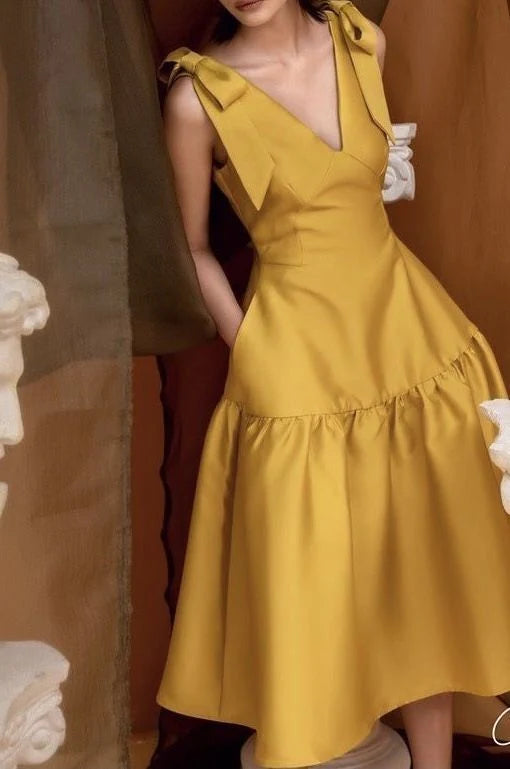 Woman wearing an elegant light-colored V-neck A-line long prom dress with ruffle straps.