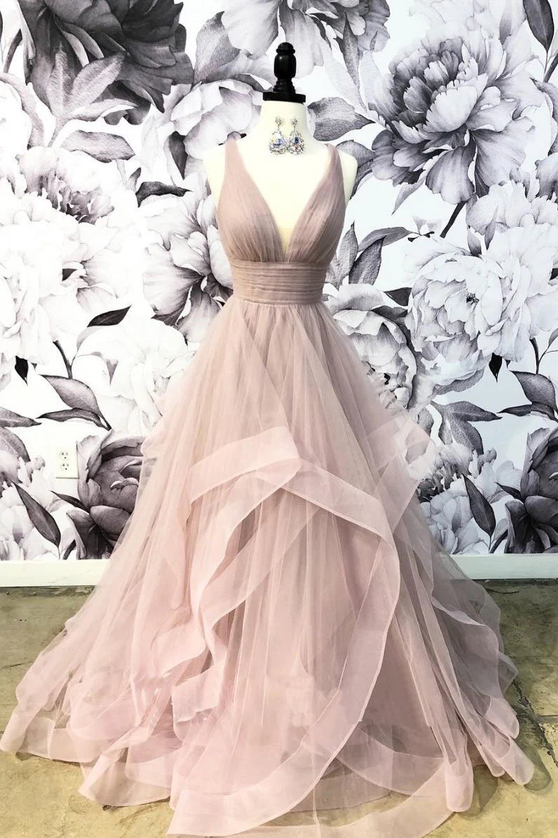 Woman wearing an elegant champagne V-neck tulle long prom dress with a cinched waist.