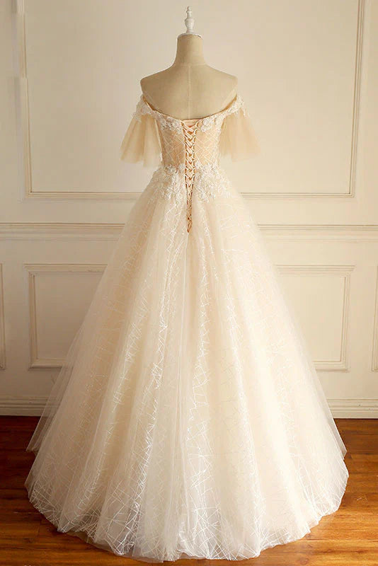 Close-up of the lace bodice and flowing tulle skirt of the champagne dress.