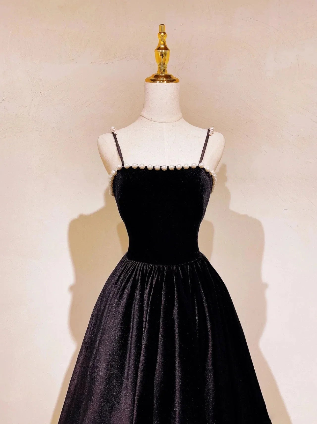 Side view of a woman wearing an elegant black velvet long V-neck A-line prom dress.