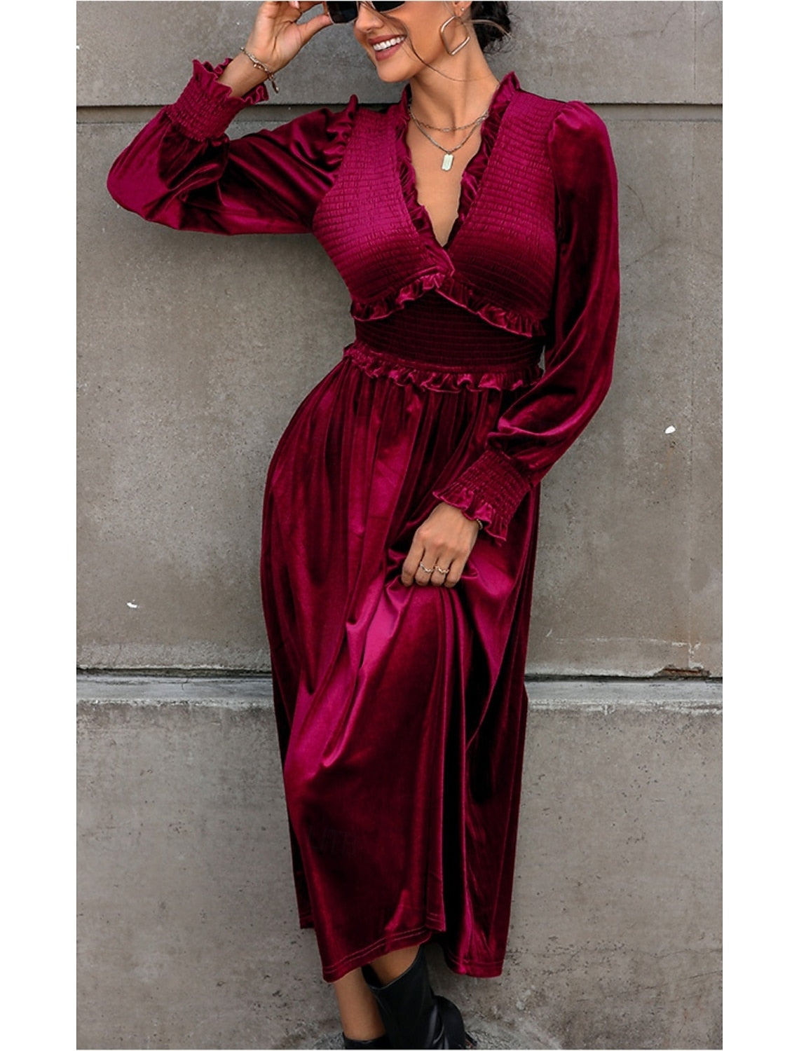 Woman posing in a flowing burgundy velvet long sleeve maxi dress.