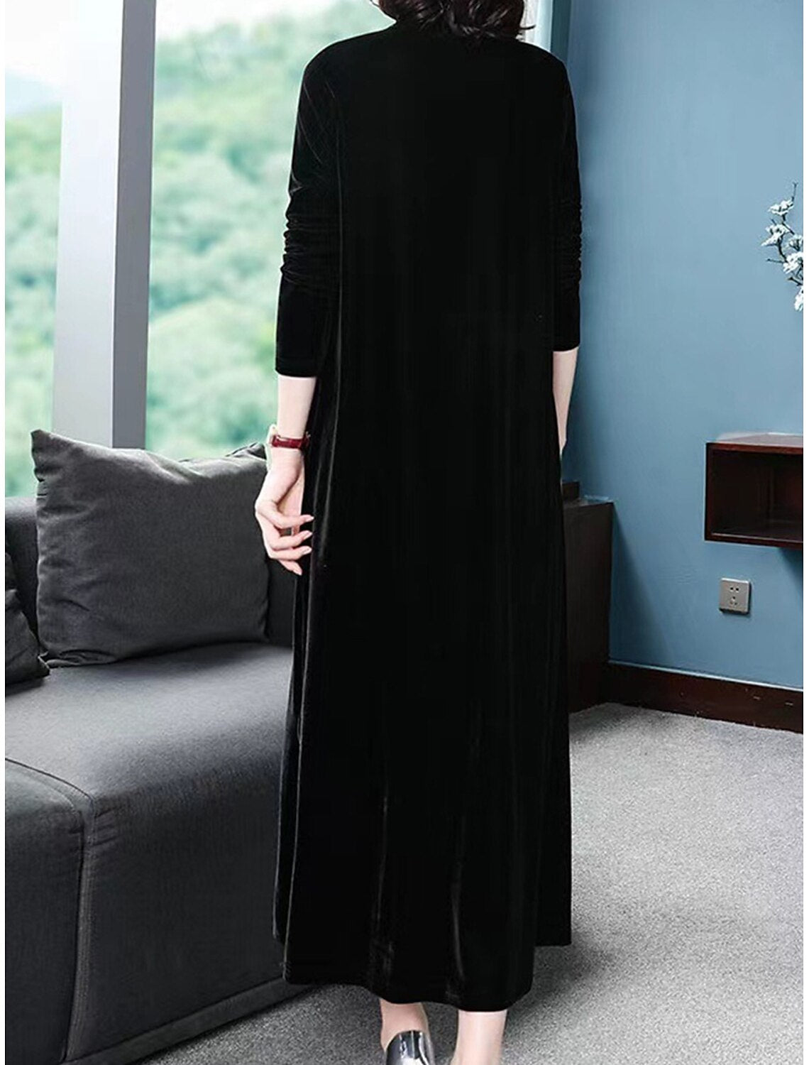 Full-length view of a woman in a black velvet long sleeve dress, showcasing the fabric and silhouette.