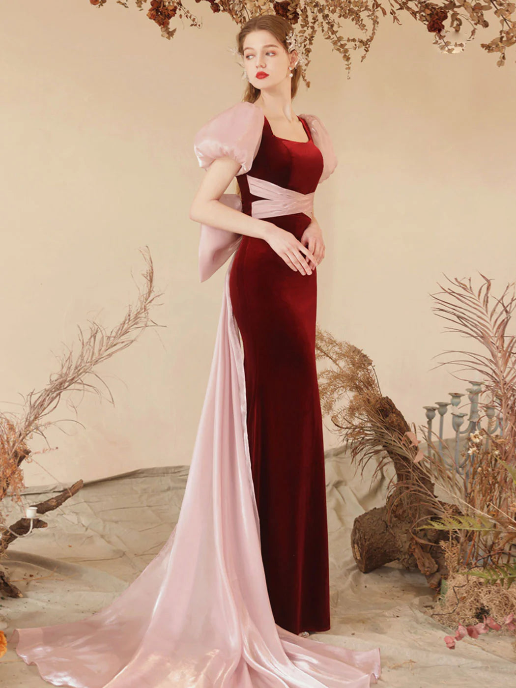 Back view of a model showcasing the train of a burgundy velvet mermaid evening dress.