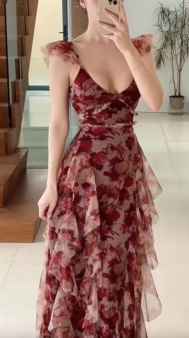 Woman wearing a long, vintage floral print A-line prom dress with a V-neck and ruffles.