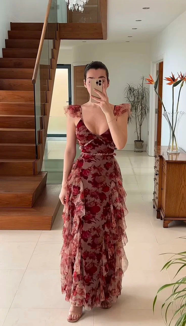 Woman posing in an elegant long chiffon prom dress featuring a floral print and irregular ruffles.