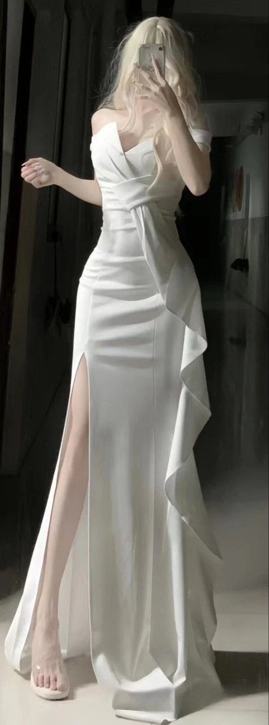 Elegant woman in a white satin sleeveless ball gown with a high leg slit.