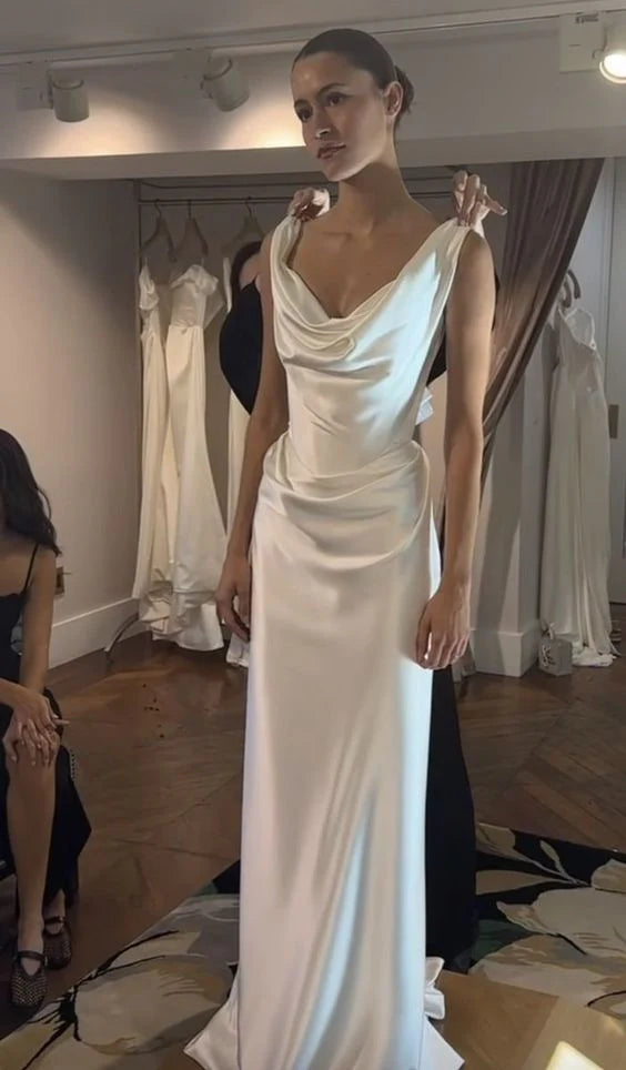 Side view of a bride in a white sheath off-shoulder satin wedding dress with a flowing train.