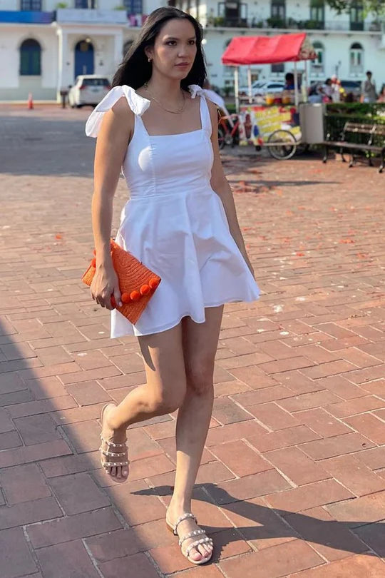 Model wearing a white square neck A-line mini party dress with bow straps.